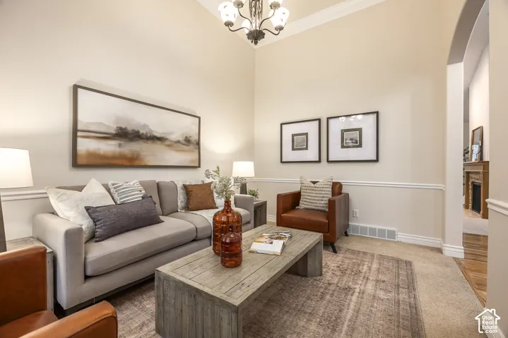 Vaulted ceiling, crown molding, chair rail molding, arched doorway, and a chandelier