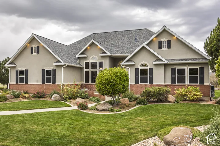 Stucco exterior with brick detailing, multi-pane windows, decorative black shutters, and an asphalt shingle roof