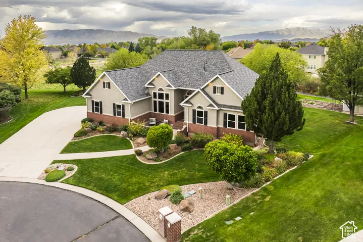 Gable roofline, light gray siding, red brick accents, dark shutters, and a concrete driveway