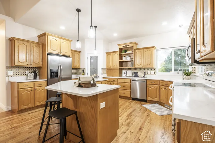 Kitchen featuring wood-finish cabinetry, stainless steel appliances, a center island with a white countertop, recessed lighting, and pendant lighting