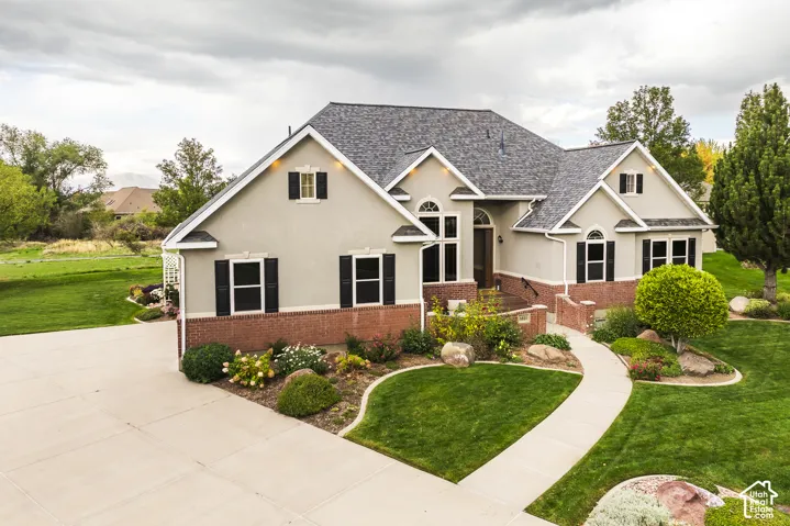 Stucco exterior with brick detailing, asphalt shingle roof, arched windows, and a curved concrete walkway