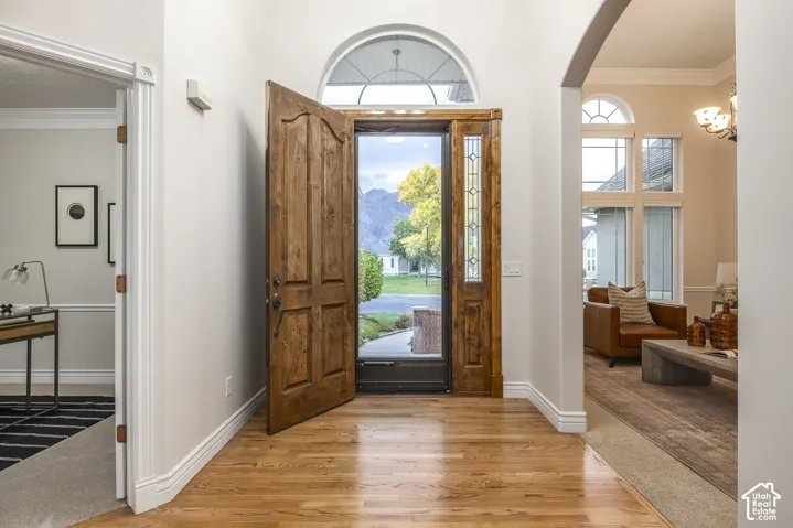 Hardwood flooring throughout the entry, arched transom window, side light window panels, crown molding, and an arched doorway