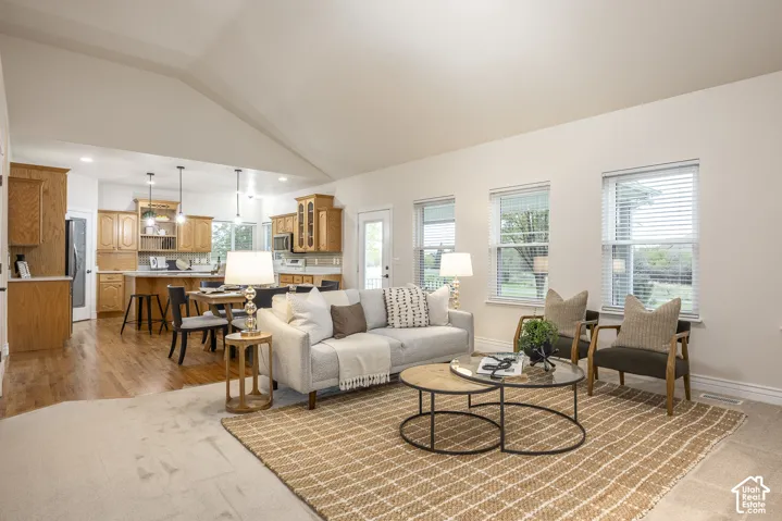 Vaulted ceiling, recessed lighting, wood-finish flooring, multiple windows, and a built-in kitchen island with pendant lighting