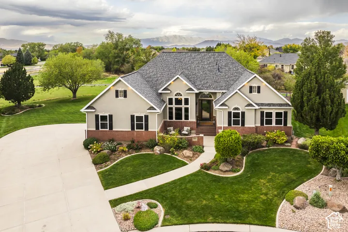 Expansive front yard with a circular driveway, mature trees, and professional landscaping
