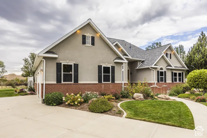 Stucco exterior with brick detailing, multi-pitch roofline, and established landscaping