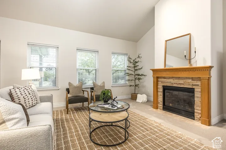 Vaulted ceiling with an integrated fireplace featuring a stone surround and wood mantel