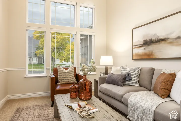 Vaulted ceiling with extensive window features, neutral wall tones, and carpet flooring