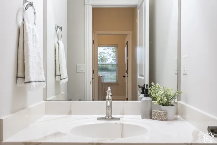 Vanity with a polished countertop, undermount sink, and wall-mounted mirror
