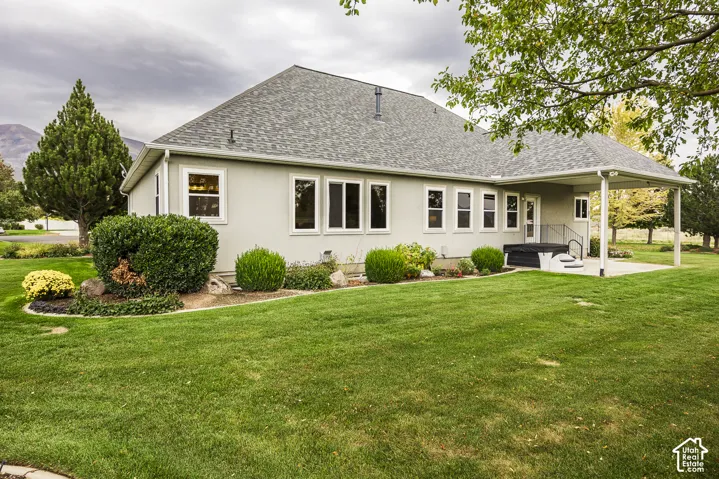 Expansive rear yard with a manicured lawn, established shrubbery, and mature trees