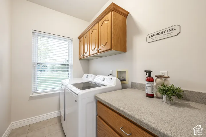 Functional laundry area featuring light-toned walls, tile flooring, and a large window with blinds