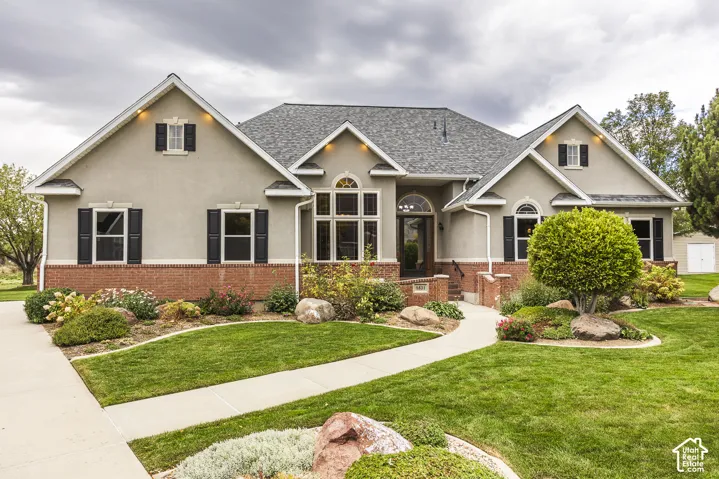 Stucco and brick exterior with a gabled roofline, featuring decorative window shutters and arched entry