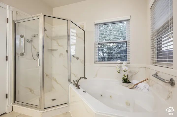 Corner glass-enclosed shower with wall-mounted grab bars and integrated shelving