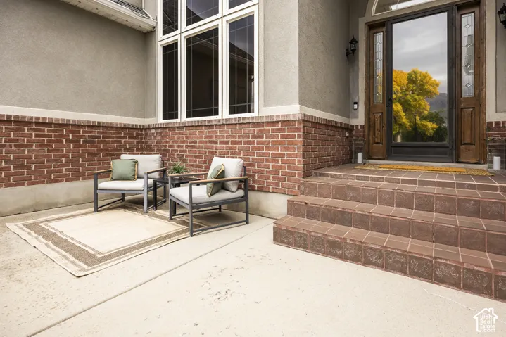 Brick and stucco exterior with multiple window panes, a solid wood entry door with glass sidelights, and tiled entry steps