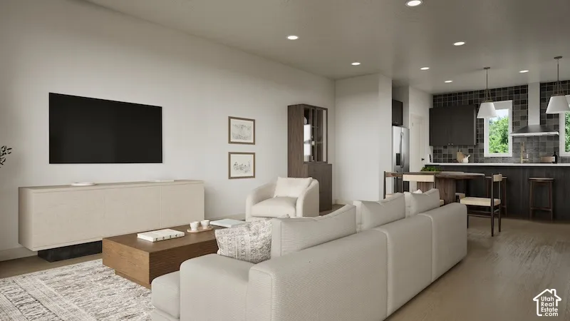 Open-concept living space featuring wood-finish flooring, recessed lighting, and a modern kitchen with dark cabinetry and a tiled backsplash