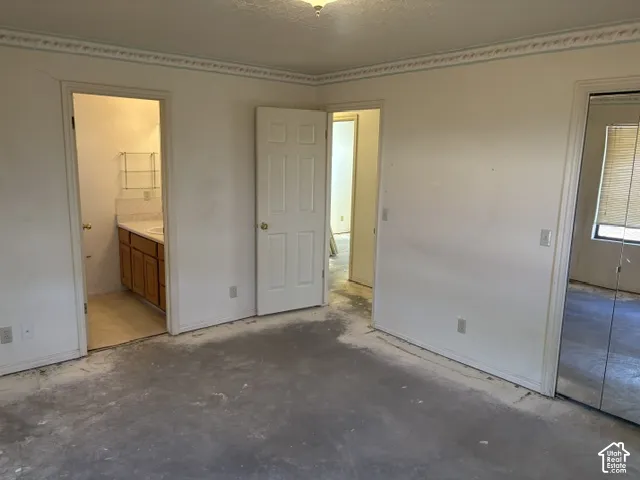 Room featuring multiple doorways, a mirrored closet, and an adjacent bathroom with a wood-finish vanity and white countertop