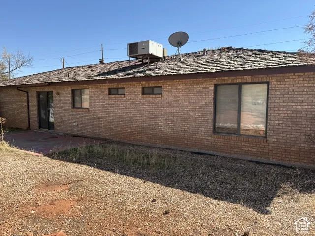 Brick exterior with a brown shingle roof, featuring multiple windows and a glass-paneled door