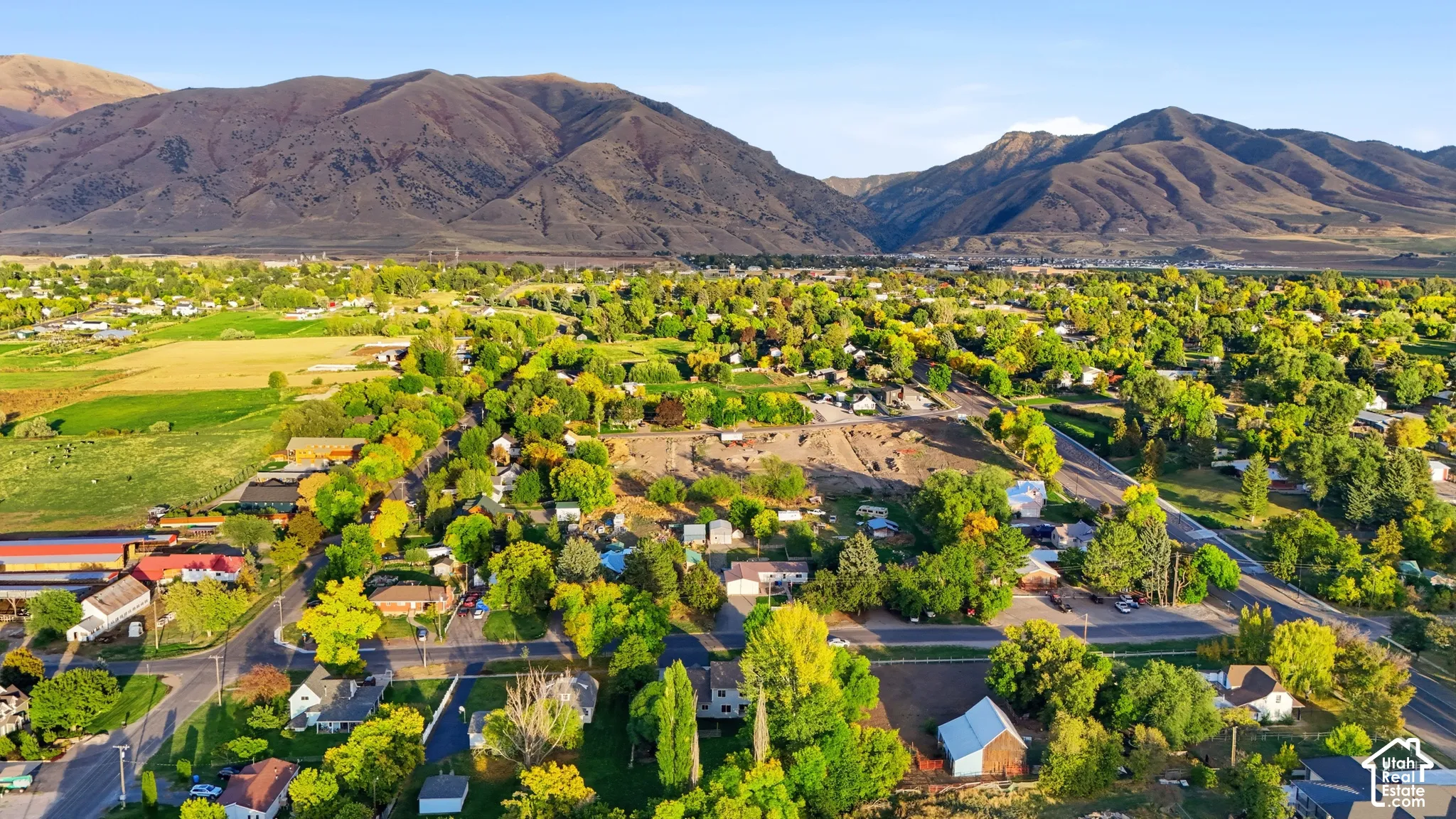 Expansive community bordered by mountainous terrain, featuring abundant mature trees and residential properties