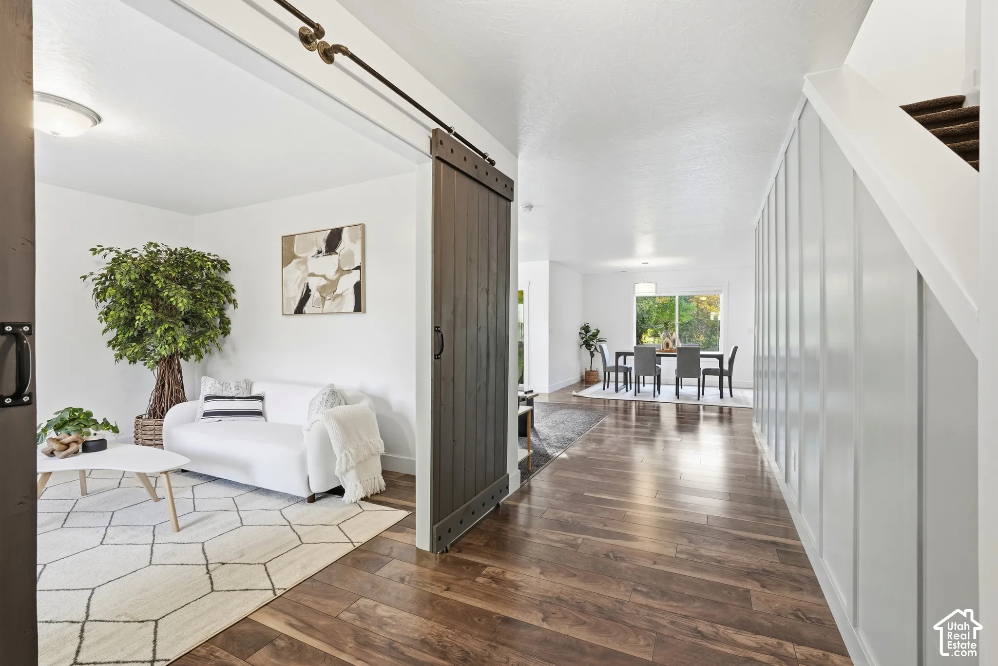 Wood-finish flooring throughout, barn-style sliding door, wainscoting detail, and a dining area with a window