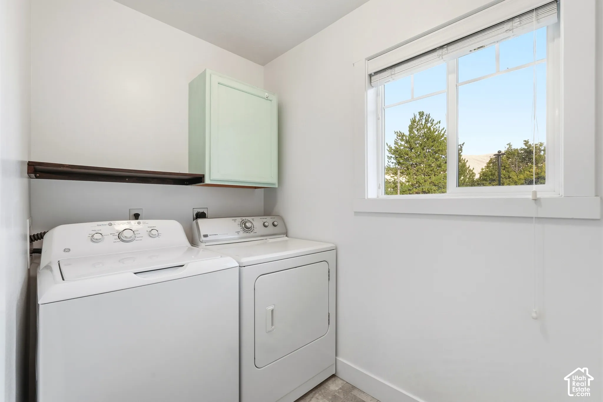 Laundry area featuring a window, overhead cabinetry, and an integrated shelf