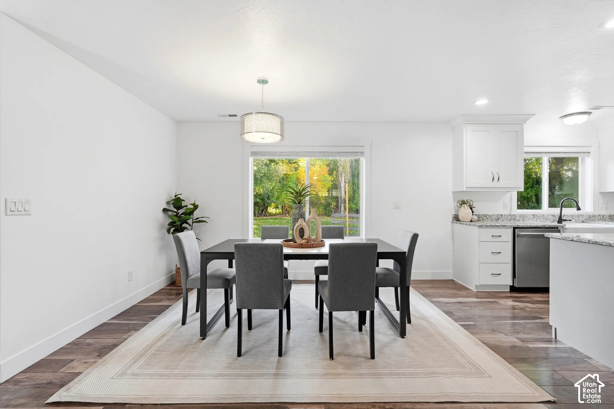 White walls, wood-finish flooring, and a contemporary drum pendant light
