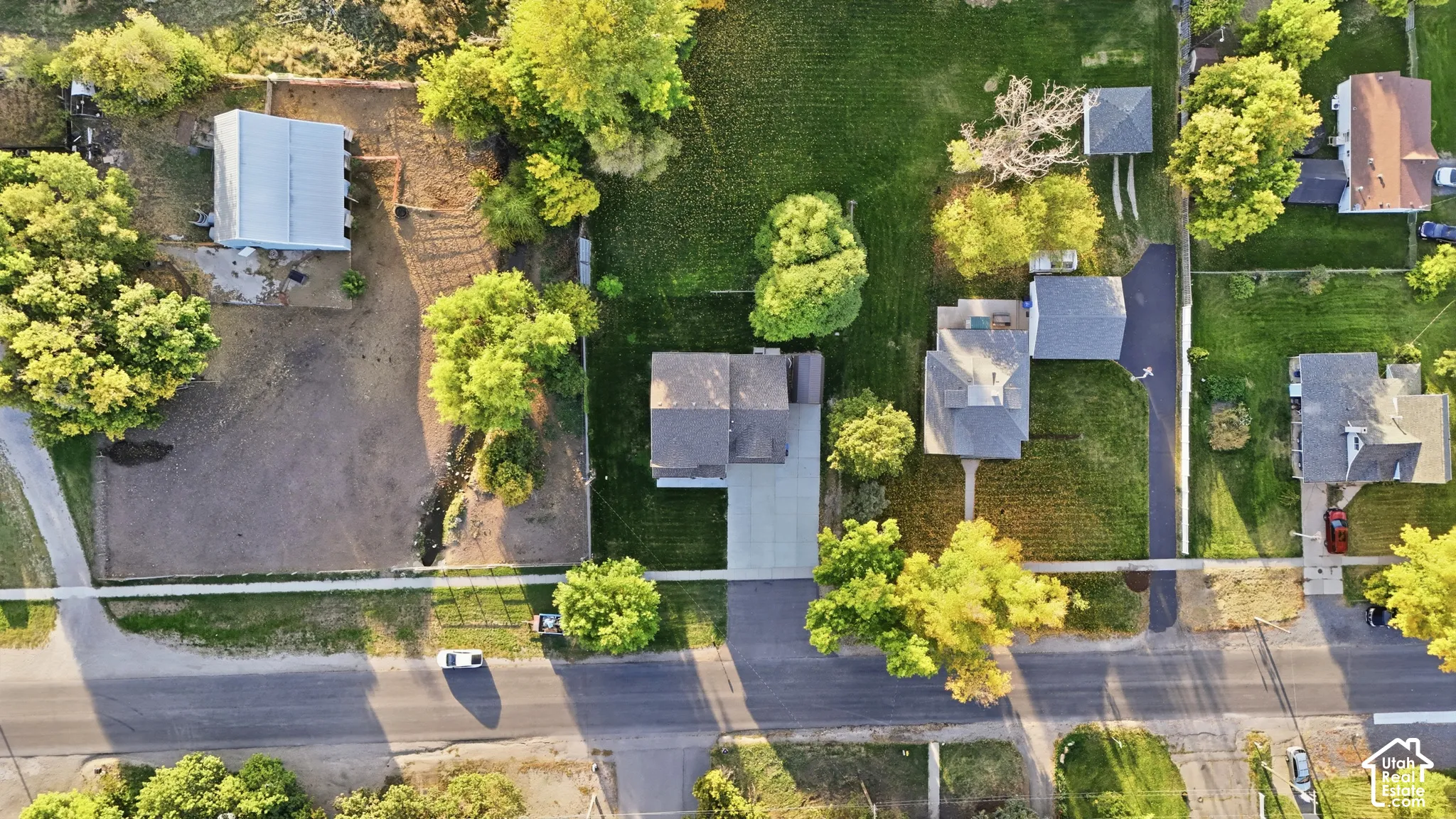 Aerial perspective showcasing multiple residential structures, expansive green lawns, mature trees, and paved roadways