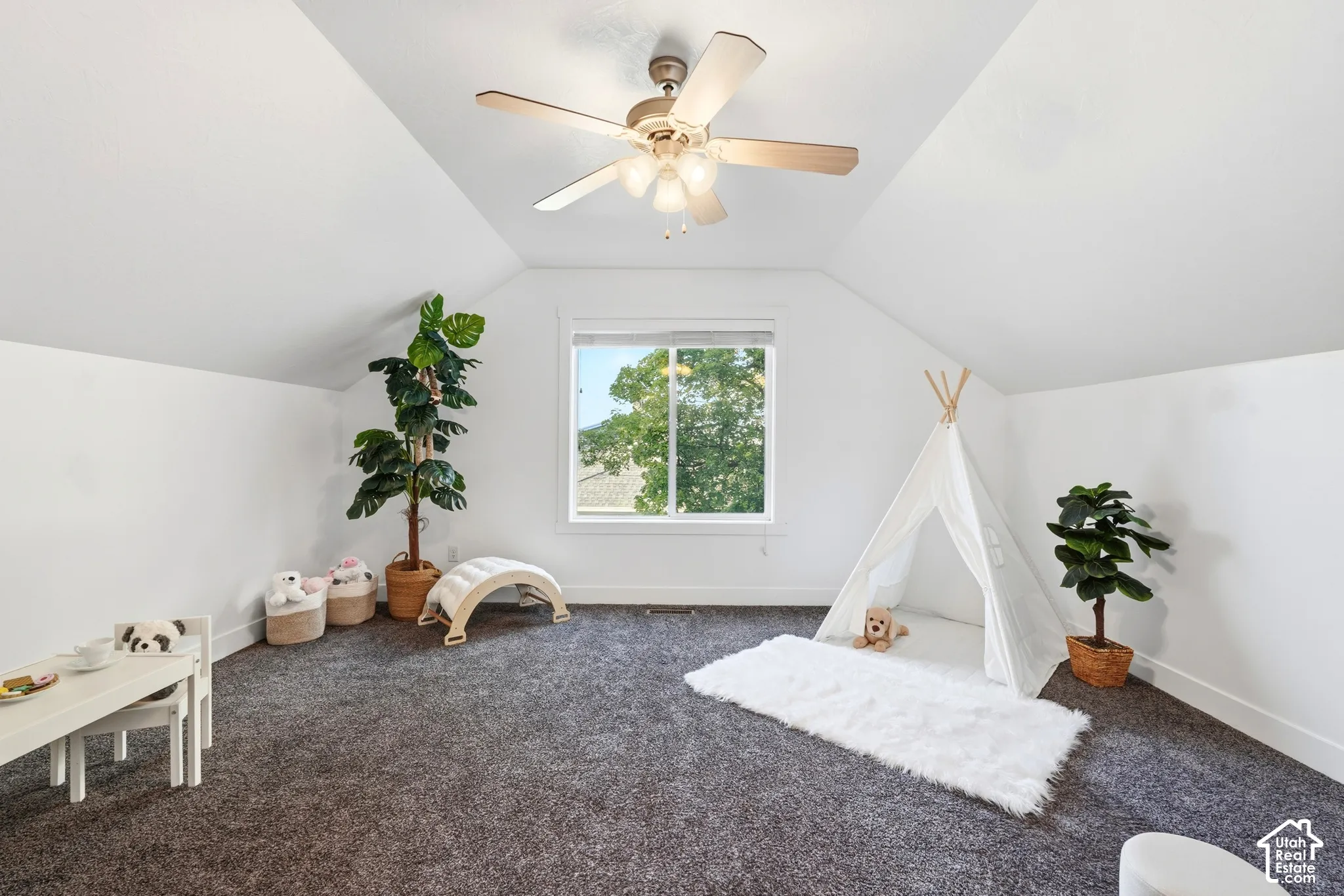 Vaulted ceilings with a ceiling fan, white walls, and dark gray carpet flooring