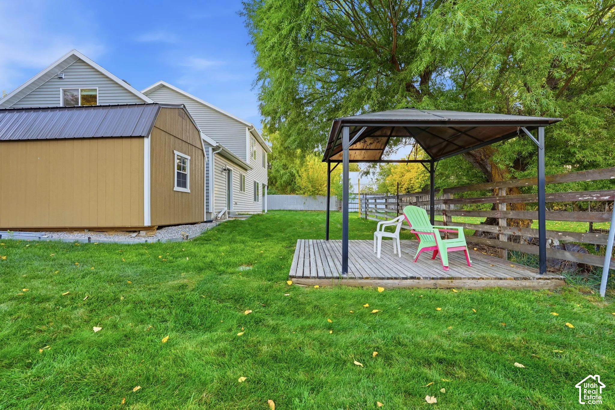 Expansive lawn featuring a wood-panel shed with a metal roof, and a freestanding wood deck with a metal gazebo