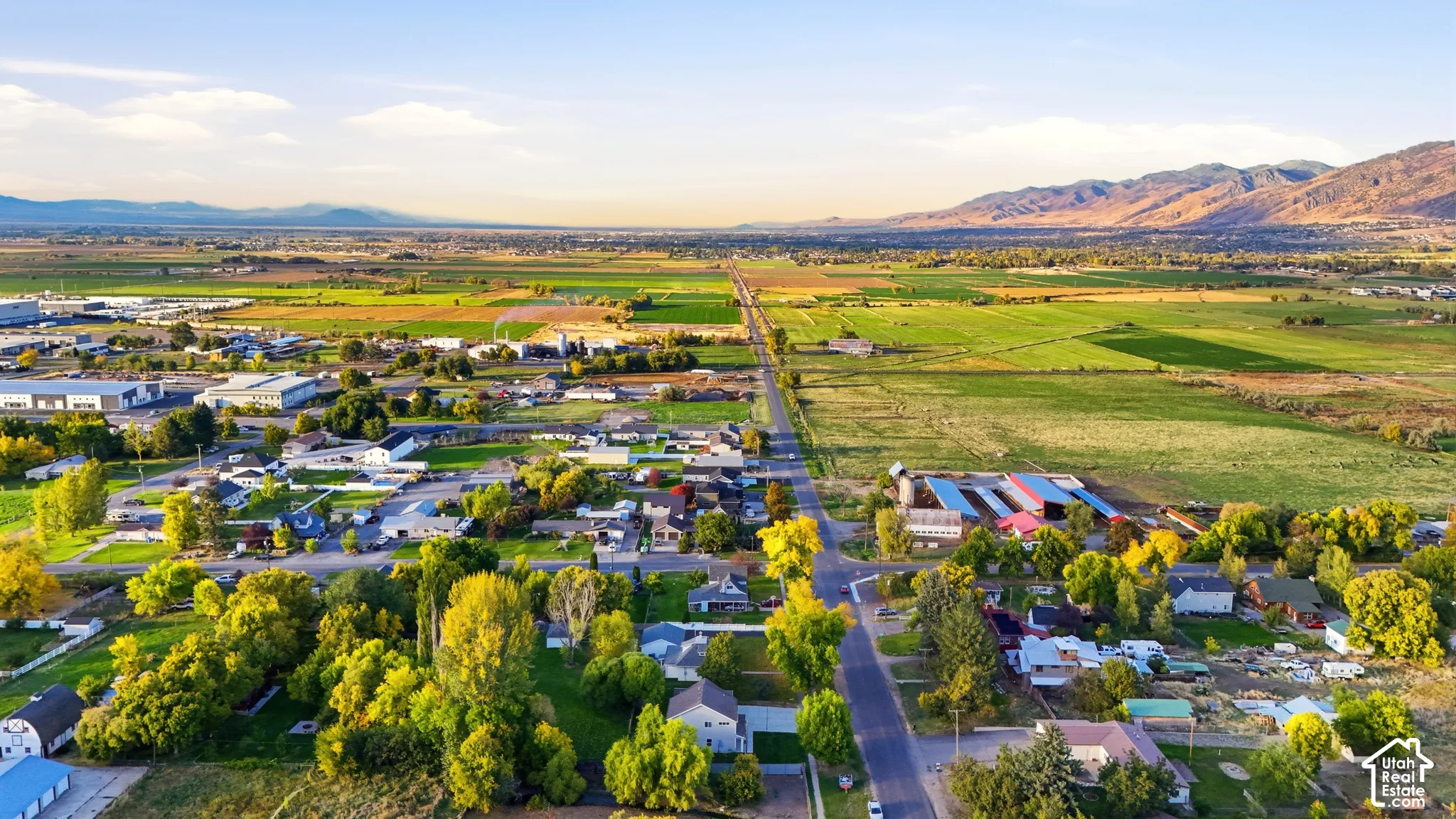 Expansive rural landscape featuring residential areas, agricultural fields, and distant mountain ranges under a clear sky