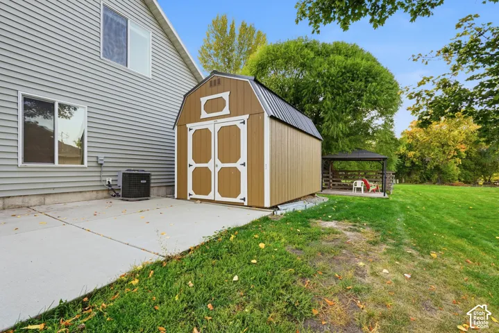 Exterior featuring siding, a concrete patio, a detached shed with double doors, and a gazebo