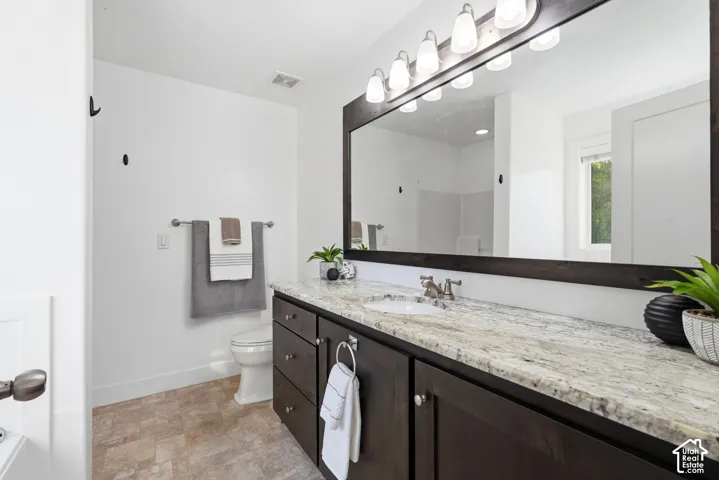Spacious vanity featuring a light-toned countertop, a single basin sink, and dark wood-finish cabinetry