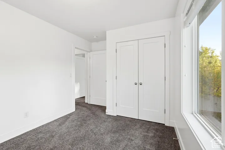 Plush gray carpeting, white trim, white walls, and a large window