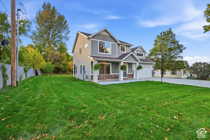 Two-story exterior with horizontal siding, stone veneer accents, an attached garage, a covered front entry, and a concrete driveway