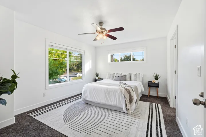 White walls, dark carpet, and a ceiling fan with integrated lighting