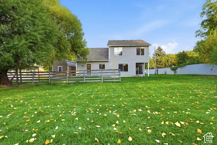 Expansive green lawn with mature trees, fenced perimeter, and a detached outbuilding