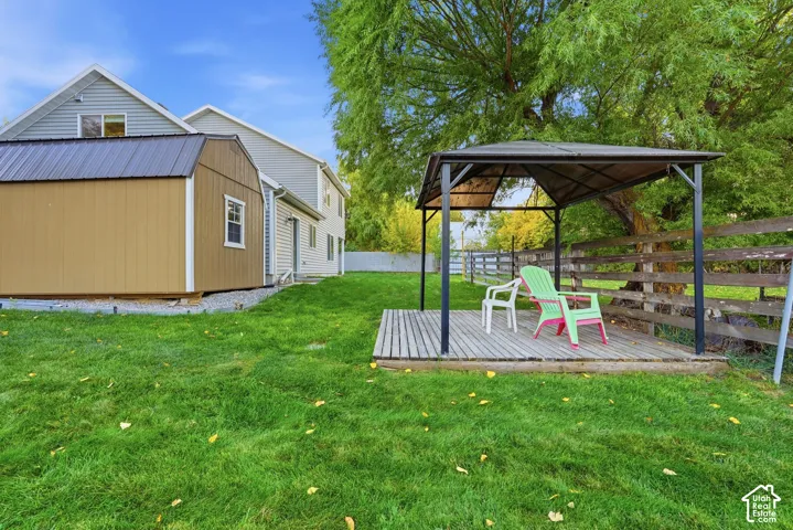 Expansive lawn featuring a wood-panel shed with a metal roof, and a freestanding wood deck with a metal gazebo