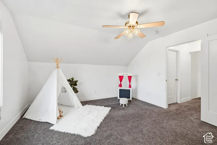Sloped ceilings with a ceiling fan, light gray carpeting, and white walls