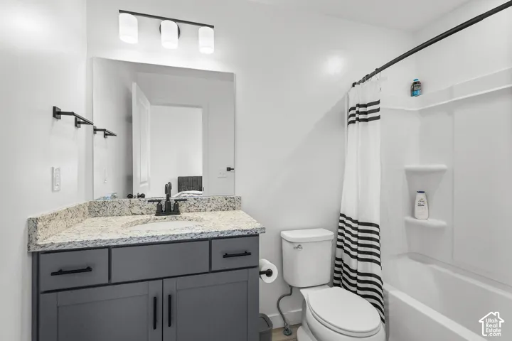 Vanity with granite countertop, integrated sink, and dark cabinetry
