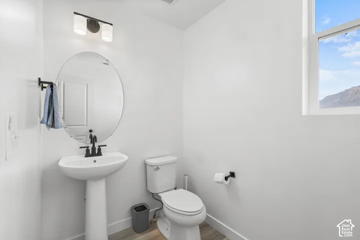 Pedestal sink with a black-finish faucet, oval mirror, and a wall-mounted light fixture