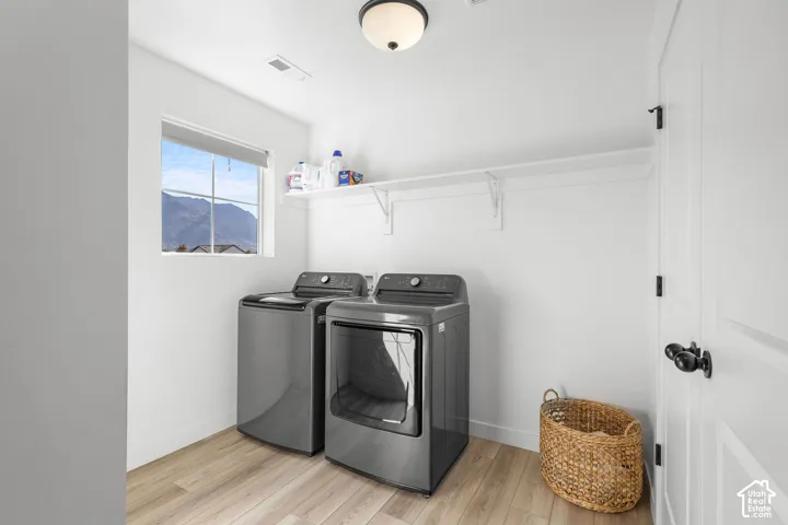 Laundry area with wood-finish flooring, white walls, built-in shelving, and a prominent window