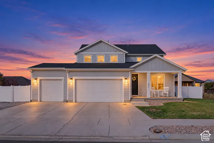 Two-story residence featuring light gray siding, a covered front porch, and a concrete driveway