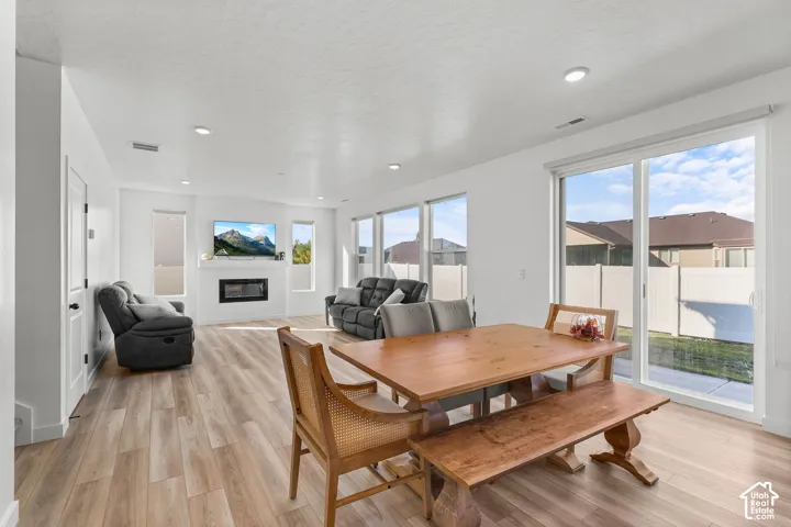 Open-concept living area featuring wood-finish flooring, recessed lighting, and a fireplace with a white mantel