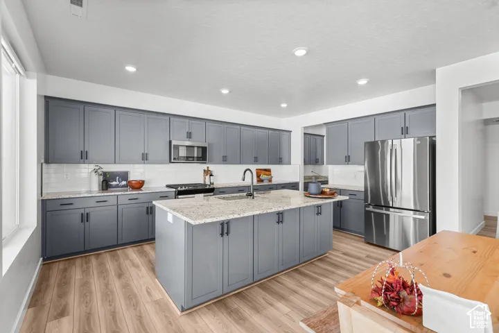 Kitchen featuring shaker-style cabinetry, a central island with countertop, stainless steel appliances, and wood-finish flooring