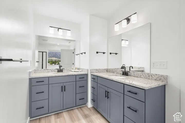 Dual vanities featuring gray cabinetry, light-toned countertops, and matte black fixtures