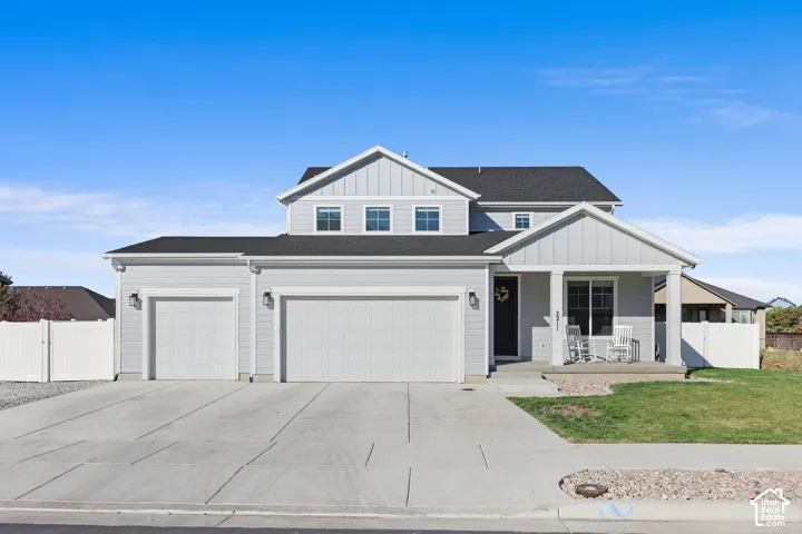 Contemporary home exterior featuring light gray siding, a dark asphalt shingle roof, a covered front porch, and a three-car garage