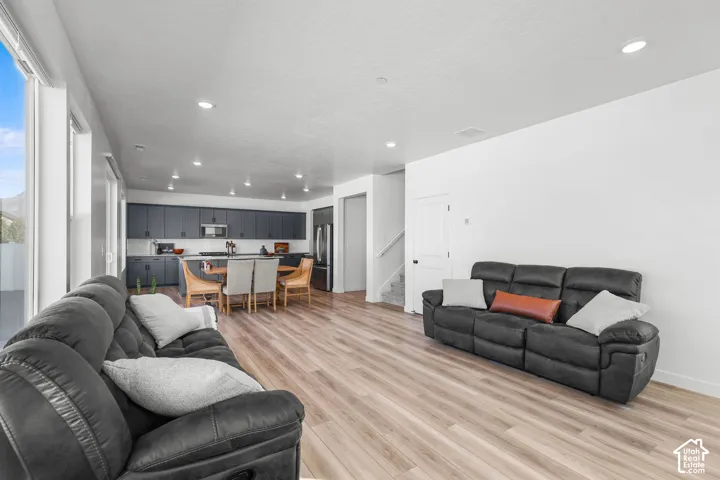 Open-concept living area featuring wood-finish flooring, recessed lighting, and a modern kitchen with dark cabinetry
