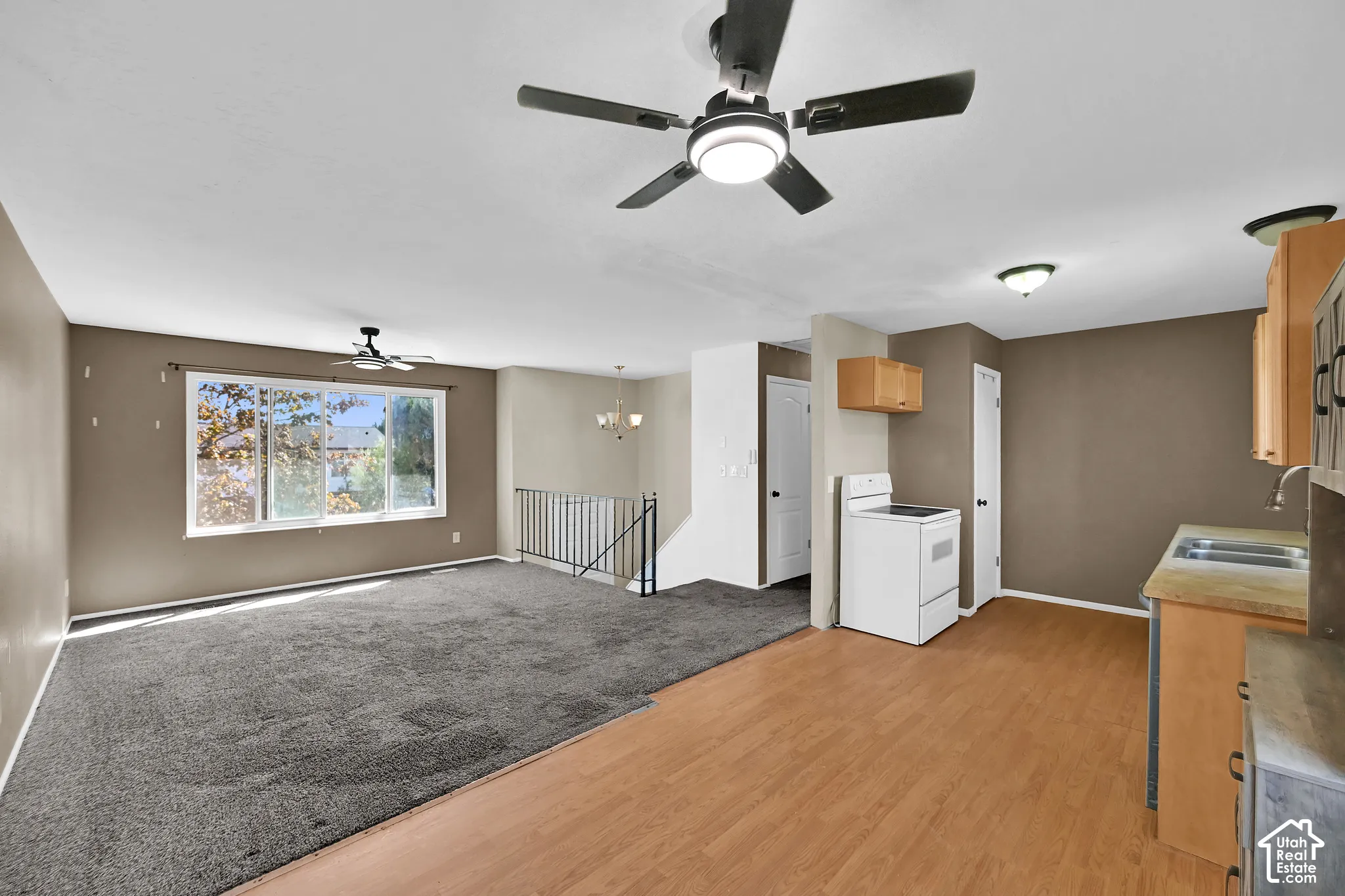 Open-concept living area with wood-finish flooring, a ceiling fan, and a large window