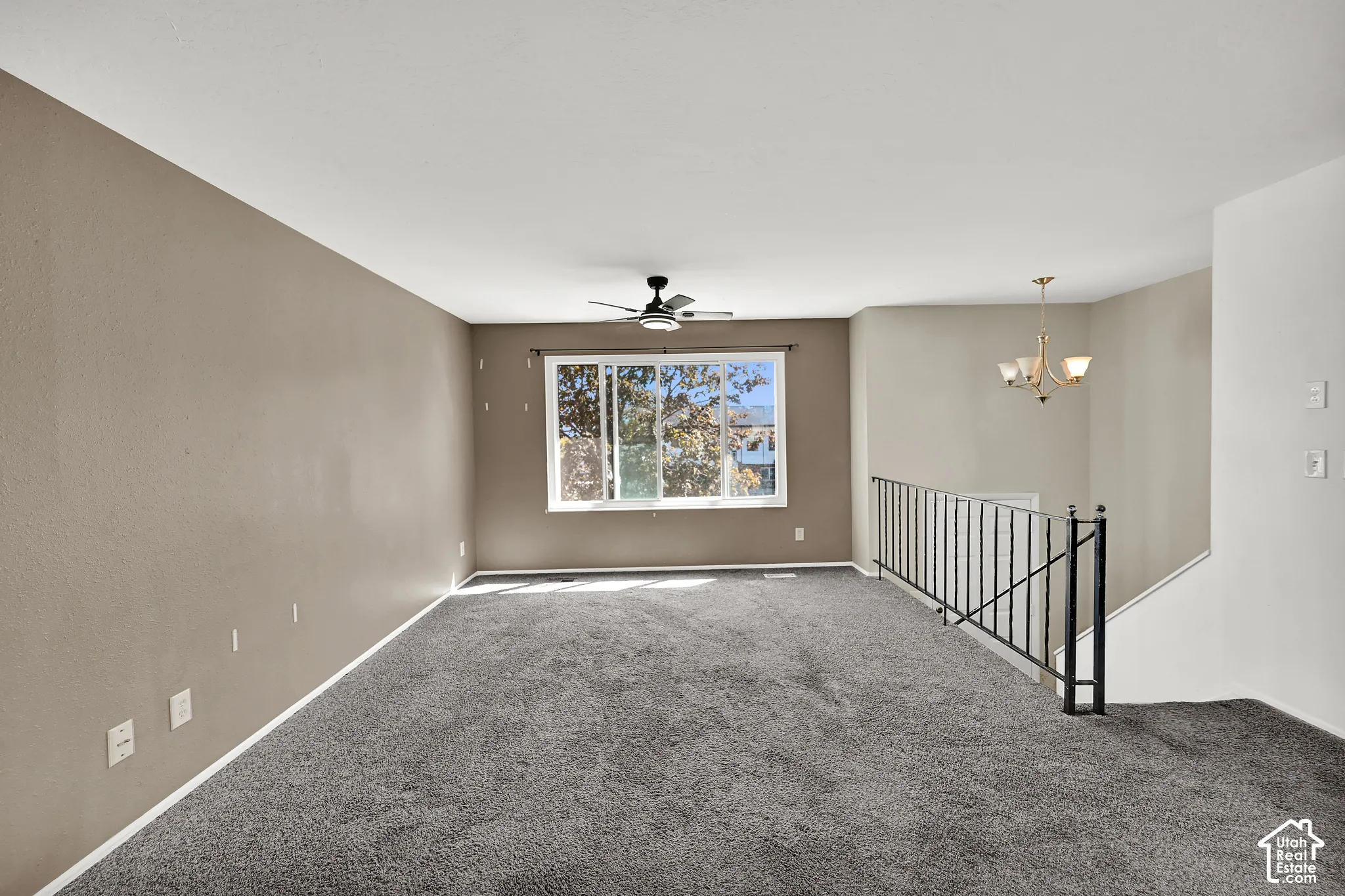 Spacious room with gray carpeting, an overhead ceiling fan, and a large window