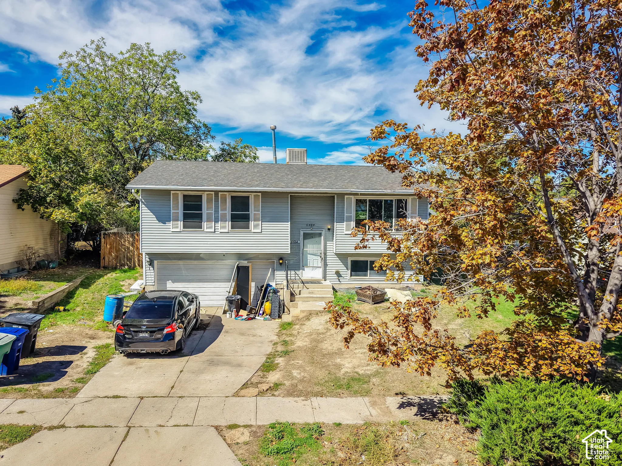 Split-level residence featuring gray siding, a two-car garage, and a concrete driveway