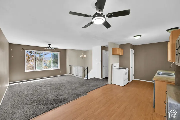Open-concept living area with wood-finish flooring, a ceiling fan, and a large window
