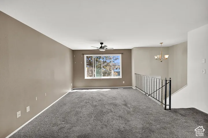 Spacious room with gray carpeting, an overhead ceiling fan, and a large window